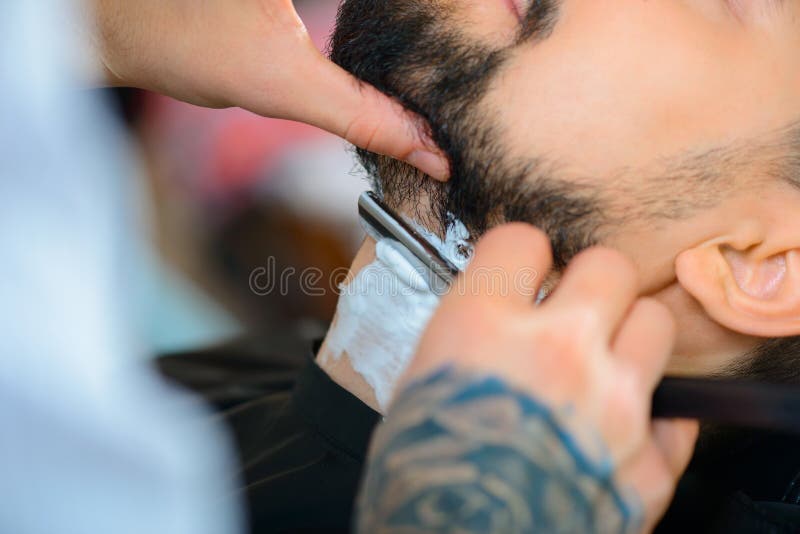 Barbeiro profissional que barbeia a barba do seu imagens de stock