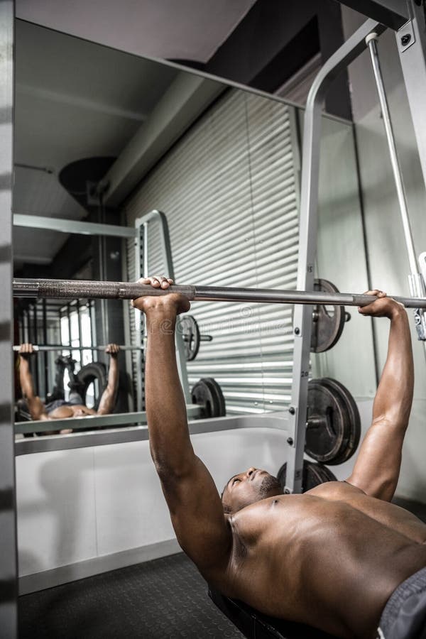 Barbell de levage d'homme sans chemise sur le banc images stock Barbell de levage d'homme sans chemise sur le banc images stock