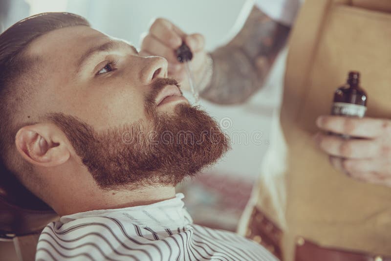 The barber applies the beard oil with a dropper