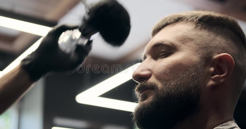 Barber cleaning face with brush and hair dryer