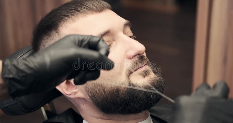 Barber doing threading procedure on face of man