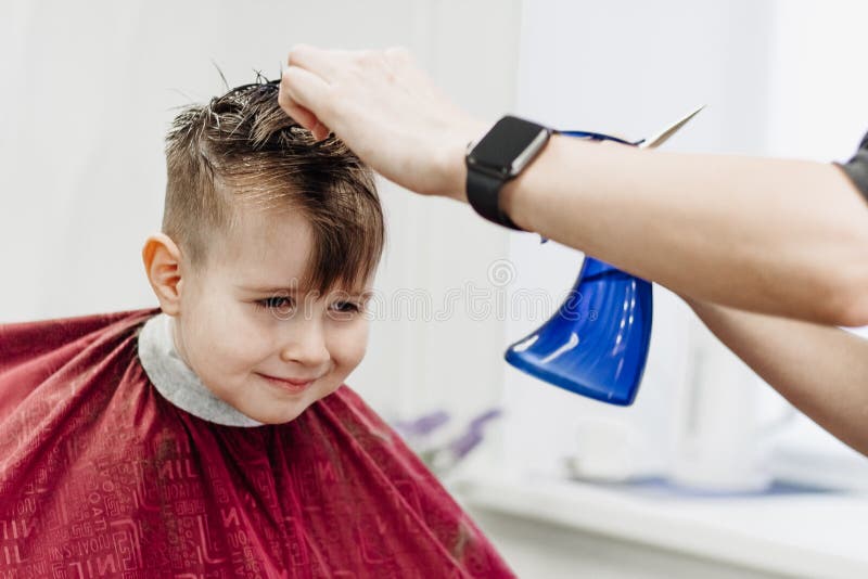 Barber`s Hands Spray the Little Boy`s Hair with a Spray Gun Stock