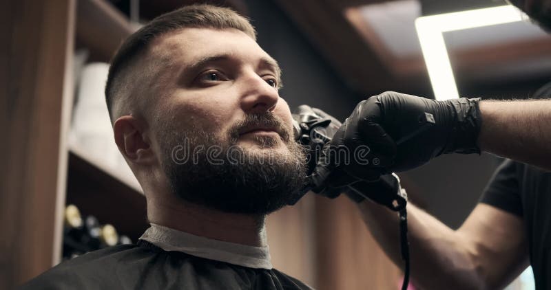 Barber shaving beard with trimmer and brush