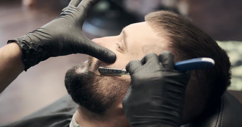 Barber shaving and styling beard using straight razor