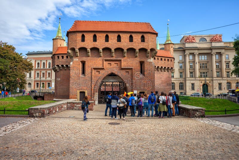 Krakow, Poland - September 23, 2019: Group of tourists on guided sightseeing tour at the Barbican Polish: Barbakan Krakowski, Gothic style city landmark from 1498. Krakow, Poland - September 23, 2019: Group of tourists on guided sightseeing tour at the Barbican Polish: Barbakan Krakowski, Gothic style city landmark from 1498