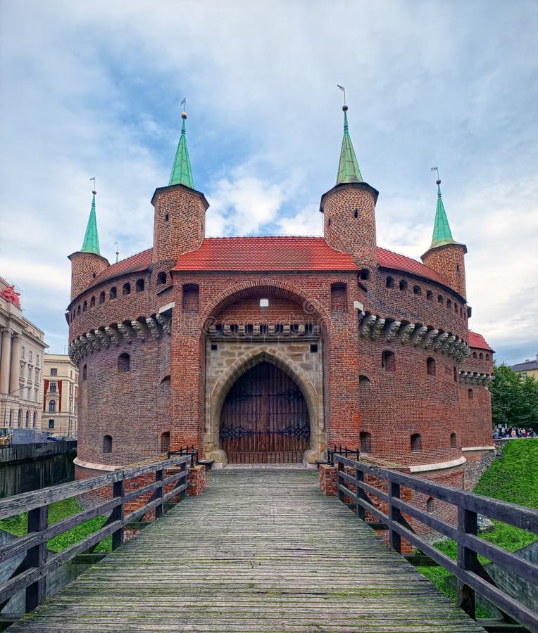 Barbican Polish: barbakan krakowski, a fortified outpost and historic gateway leading into the Old Town of Krakow, Poland, built around 1498. A view with old wooden bridge at side of western gate. Barbican Polish: barbakan krakowski, a fortified outpost and historic gateway leading into the Old Town of Krakow, Poland, built around 1498. A view with old wooden bridge at side of western gate.