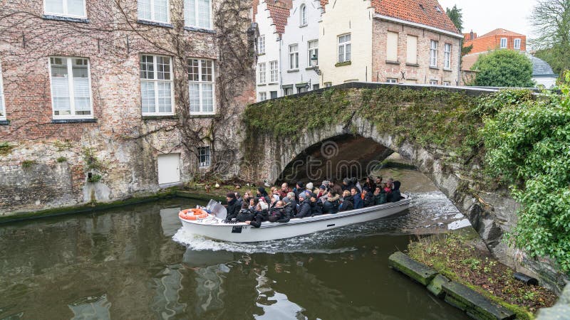 Barca facente un giro turistico turistica sul canale a Bruges nell'inverno, Bruges, Belgio immagine stock libera da diritti Barca facente un giro turistico turistica sul canale a Bruges nell'inverno, Bruges, Belgio immagine stock libera da diritti