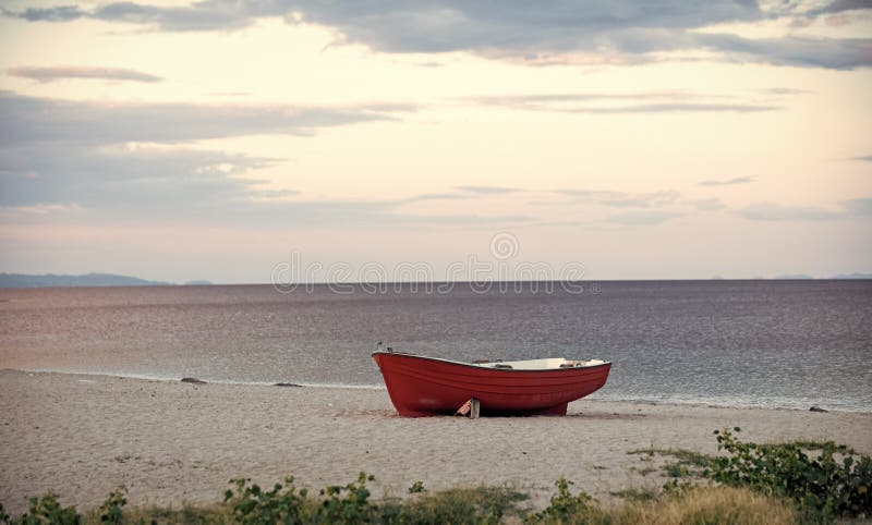 Barca sulla spiaggia Barca di Fishermens al litorale, sulla sabbia il giorno nuvoloso con il mare su fondo Peschereccio sulla spi fotografie stock Barca sulla spiaggia Barca di Fishermens al litorale, sulla sabbia il giorno nuvoloso con il mare su fondo Peschereccio sulla spi fotografie stock