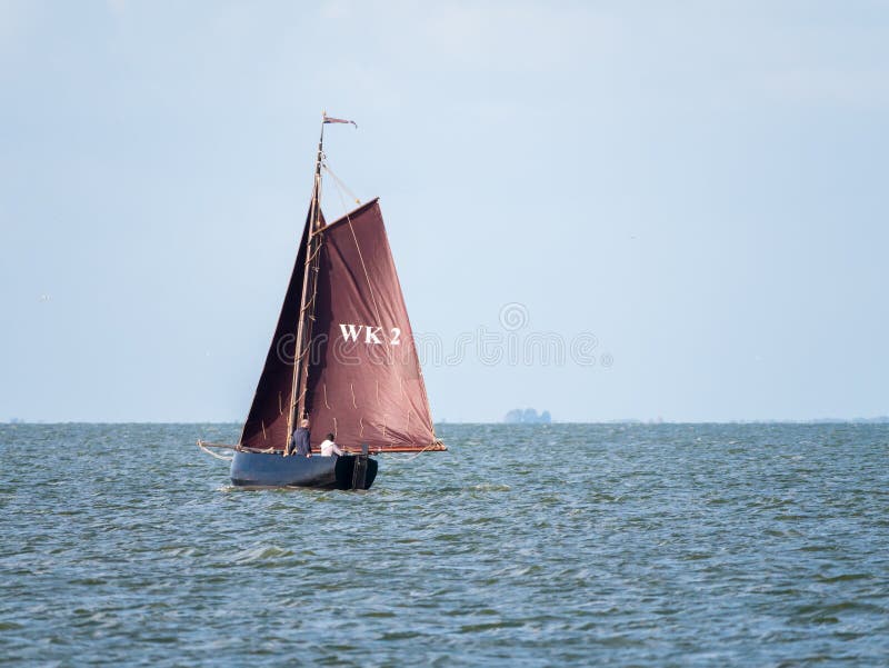 Barca a vela con le vele marroni che navigano sul lago IJsselmeer vicino a Enkhui immagine stock Barca a vela con le vele marroni che navigano sul lago IJsselmeer vicino a Enkhui immagine stock