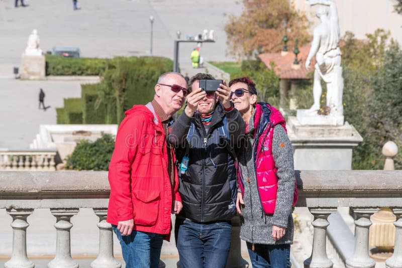 Barcellona, Spagna - 12 marzo 2019: Un gruppo di turisti che fanno i selfies facendo uso di uno smartphone fotografia stock Barcellona, Spagna - 12 marzo 2019: Un gruppo di turisti che fanno i selfies facendo uso di uno smartphone fotografia stock