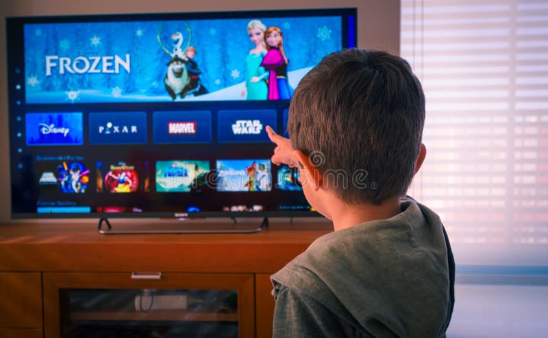 Barcelona, Spain. May 2019: Back view image of cute little boy watching the new Disney plus platform on TV
