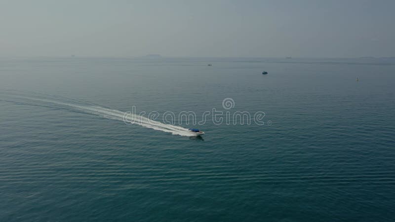 Barco a alta velocidade corre ao longo da superfície do mar em águas tropicais, vista de cima.