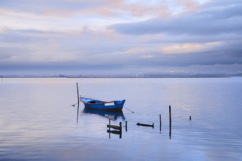 Barco azul en el medio del lago debajo del rosa y del cielo azul foto de archivo libre de regalías Barco azul en el medio del lago debajo del rosa y del cielo azul foto de archivo libre de regalías