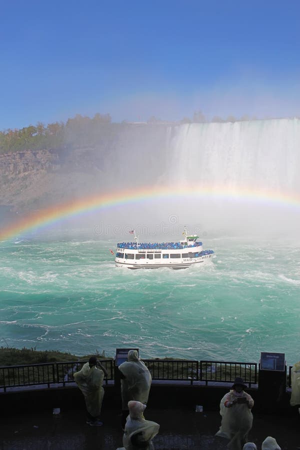 Barco da excursão de Niagara Falls do relógio dos turistas sob um vert completo do arco-íris foto de stock royalty free Barco da excursão de Niagara Falls do relógio dos turistas sob um vert completo do arco-íris foto de stock royalty free