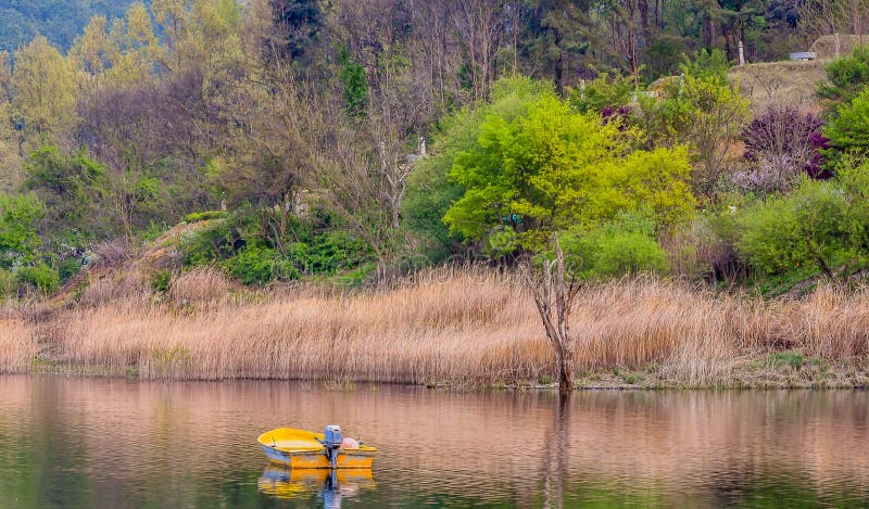 Barco de pesca amarillo que flota en el pequeño lago foto de archivo Barco de pesca amarillo que flota en el pequeño lago foto de archivo