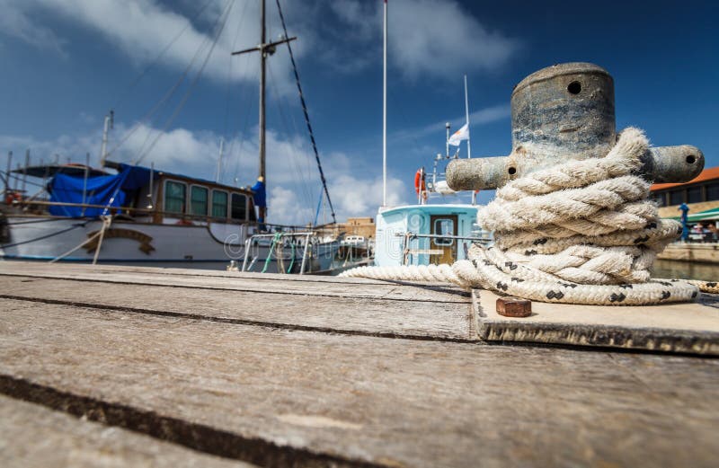 Boat docking point at a marina - rope fixed around a belay in a small harbor. Boat docking point at a marina - rope fixed around a belay in a small harbor