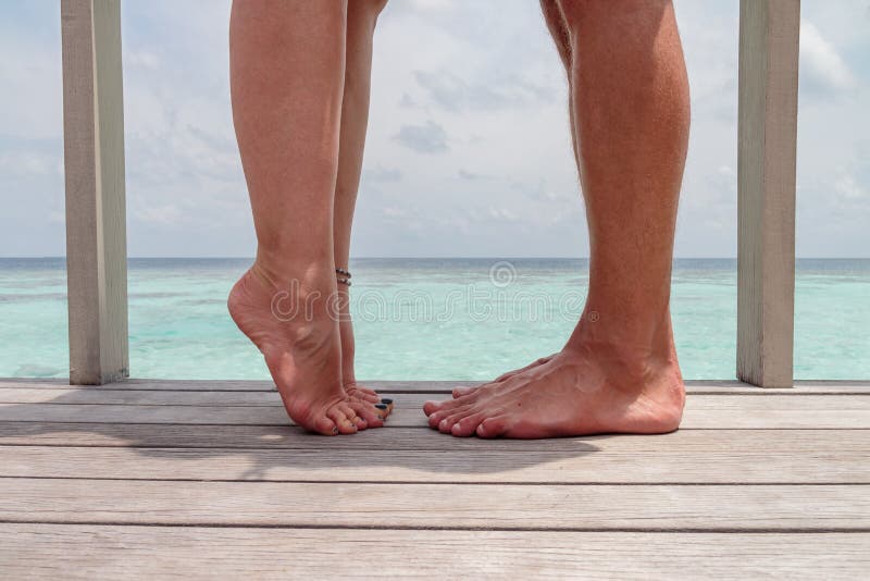 Closeup photo of woman and man legs, girl with raised leg. Couple kissing, over sea background, he vs she royalty free stock images Closeup photo of woman and man legs, girl with raised leg. Couple kissing, over sea background, he vs she royalty free stock images