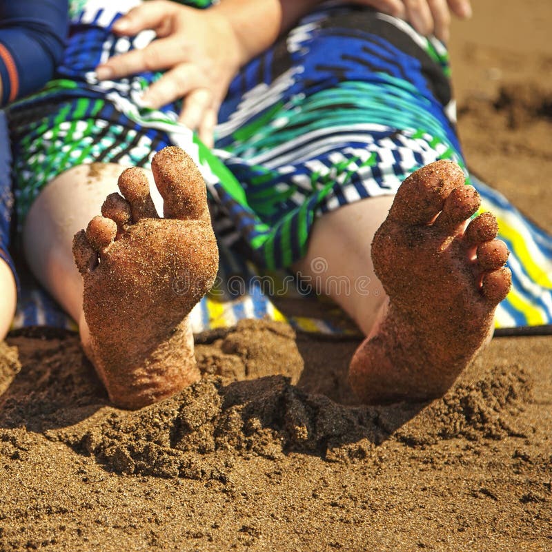A woman's bare sandy feet at the beach - square. A woman's bare sandy feet at the beach - square.