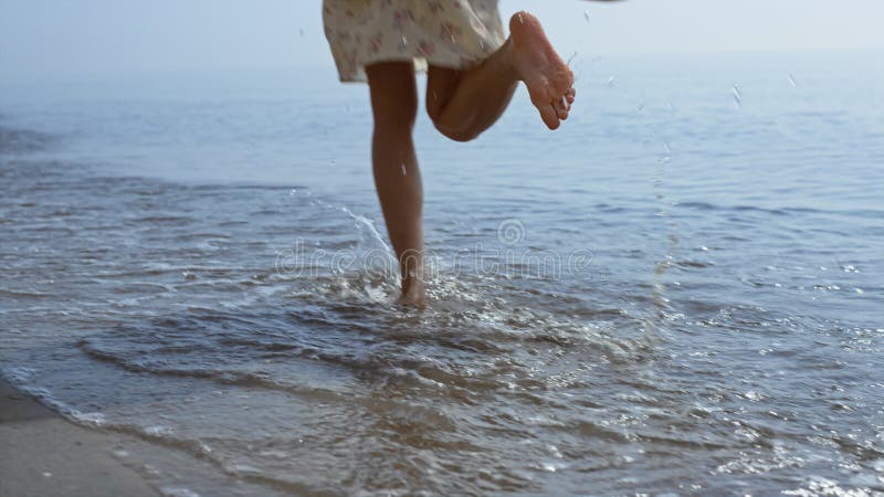 Bare woman legs jumping on sea waves close up. Girl feet splashing in water.