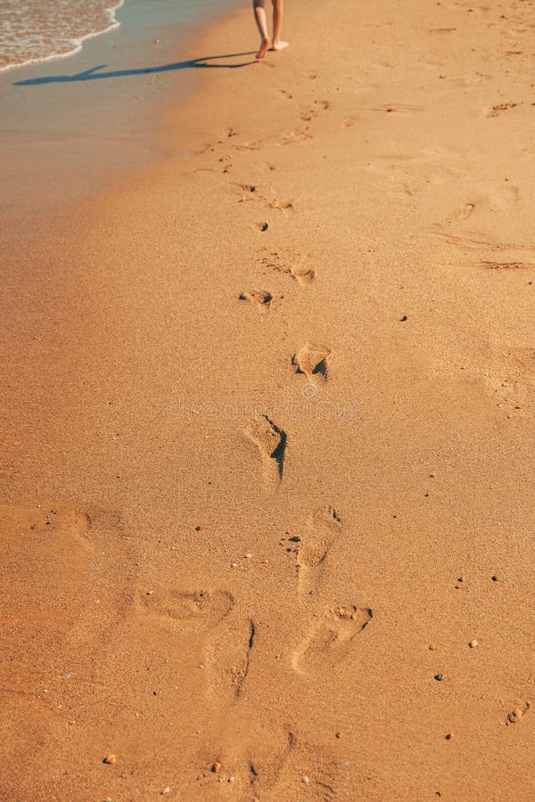 Barefoot boy walking on seaside beach sand in summer stock photo