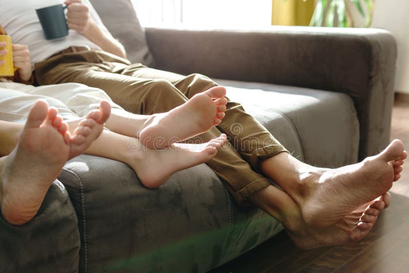 Barefoot family sitting on sofa in the living room royalty free stock image