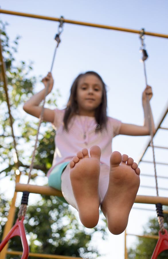 Barefoot girl swings on a swing in the playground