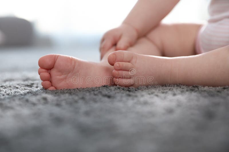 Barefoot little child with sitting on grey carpet indoors stock photo Barefoot little child with sitting on grey carpet indoors stock photo