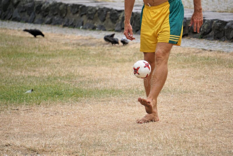 Barefoot man kicks soccer ball on grassy field stock photos Barefoot man kicks soccer ball on grassy field stock photos