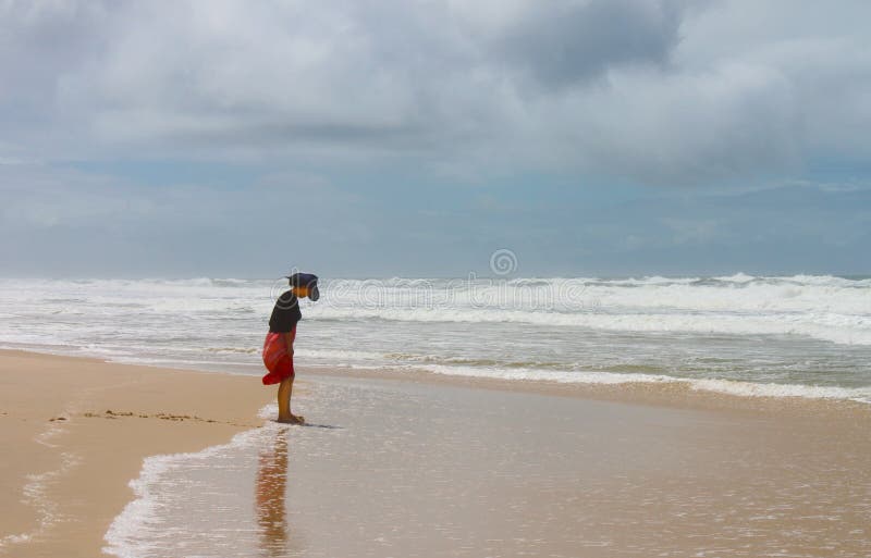 Barefoot woman in hat and dress looks down at her mud covered feet on beach on the Gold Coast of Queensland Australia 02-23-2015 royalty free stock photos Barefoot woman in hat and dress looks down at her mud covered feet on beach on the Gold Coast of Queensland Australia 02-23-2015 royalty free stock photos