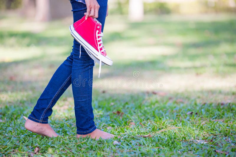 Barefoot woman holding shoes