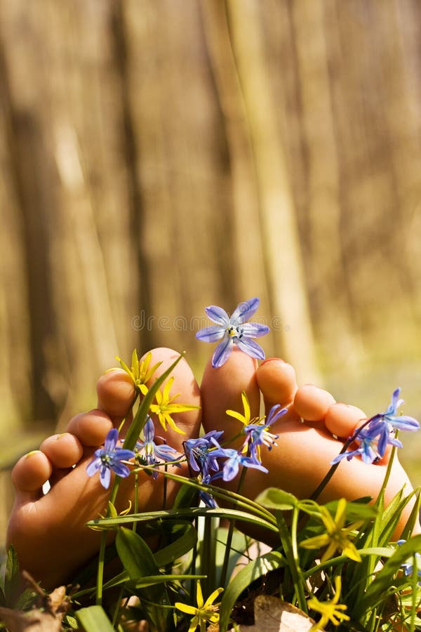 Barefooted tender woman s feet in spring flowers