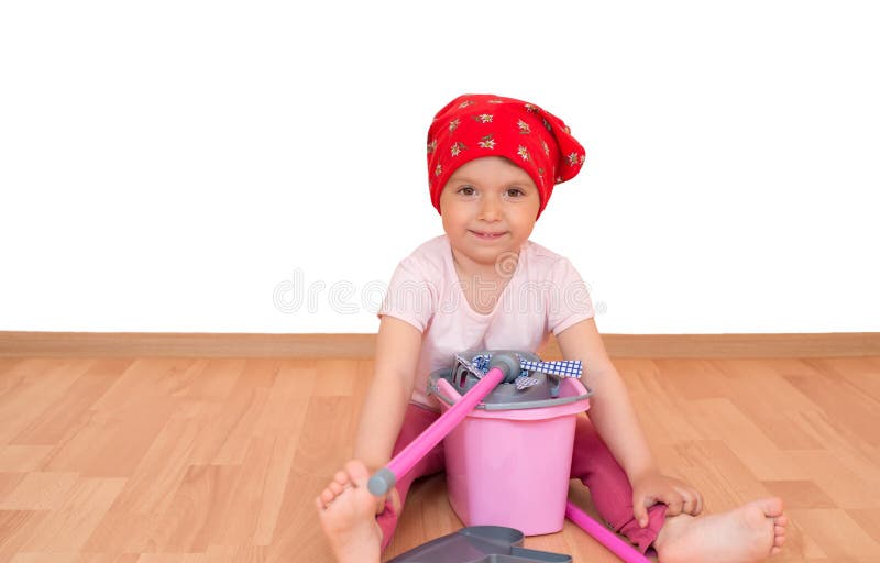 Barfota liten flicka med leksaklokalvårdutrustning som sitter på det isolerade golvet royaltyfri fotografi Barfota liten flicka med leksaklokalvårdutrustning som sitter på det isolerade golvet royaltyfri fotografi
