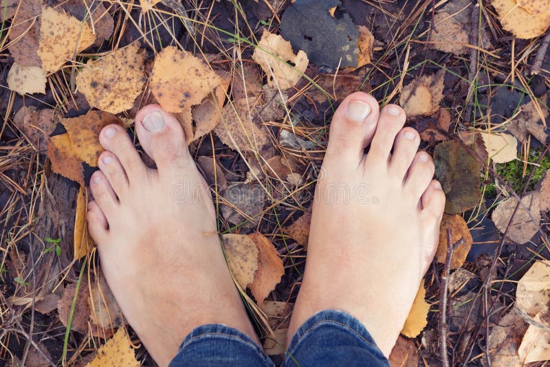 Barfüßigperson, die aus den Grund im Herbstwald steht lizenzfreies stockbild