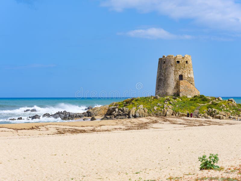 The symbol of the city of Bari Sardo, `Torre di Barì`, a tower built on a rocky outcrop on the beach with beige sand and sea with crystalline water. The symbol of the city of Bari Sardo, `Torre di Barì`, a tower built on a rocky outcrop on the beach with beige sand and sea with crystalline water