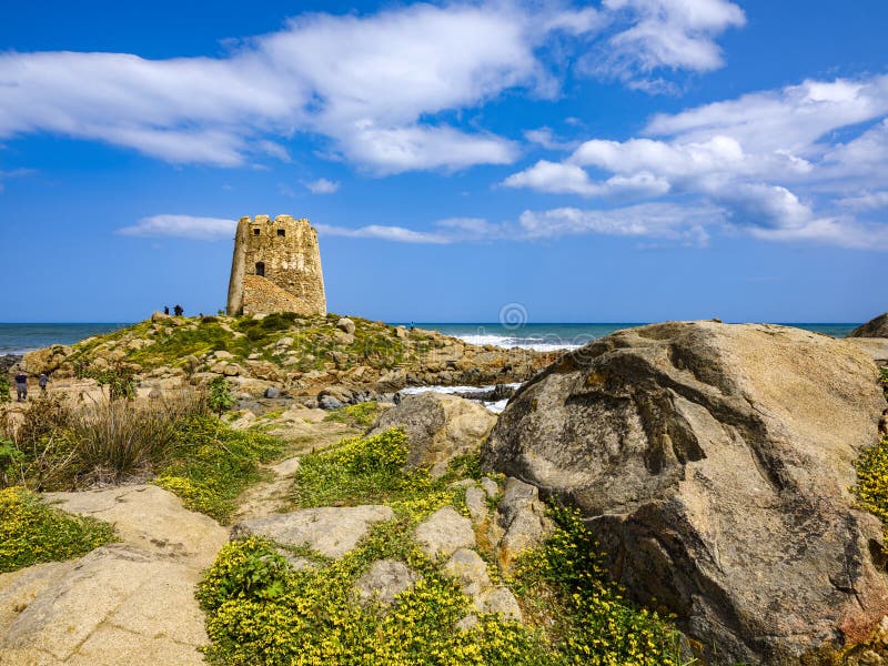 The symbol of the city of Bari Sardo, `Torre di Barì`, a tower built on a rocky outcrop on the beach with beige sand and sea with crystalline water. The symbol of the city of Bari Sardo, `Torre di Barì`, a tower built on a rocky outcrop on the beach with beige sand and sea with crystalline water