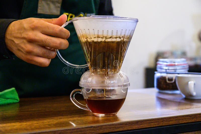 Barista brewing pour over coffee in transparent dripper royalty free stock photo