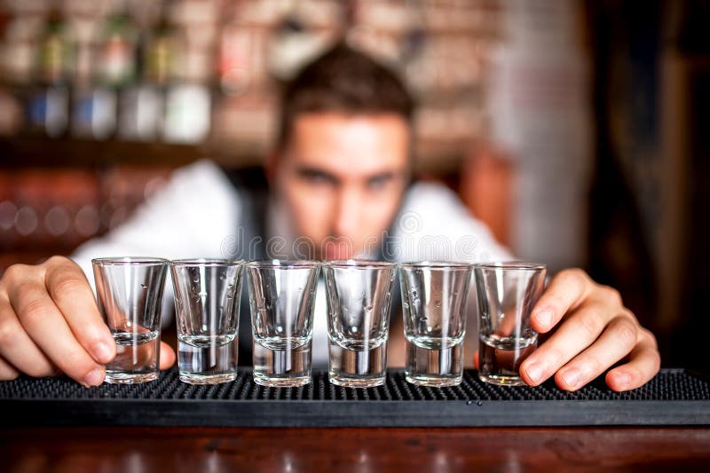Barista che prepara e che allinea i vetri di colpo per le bevande alcoliche fotografie stock libere da diritti Barista che prepara e che allinea i vetri di colpo per le bevande alcoliche fotografie stock libere da diritti