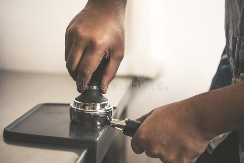 Barista facendo uso di pigiatura per il chicco di caffè di recente arrostito fotografia stock libera da diritti Barista facendo uso di pigiatura per il chicco di caffè di recente arrostito fotografia stock libera da diritti