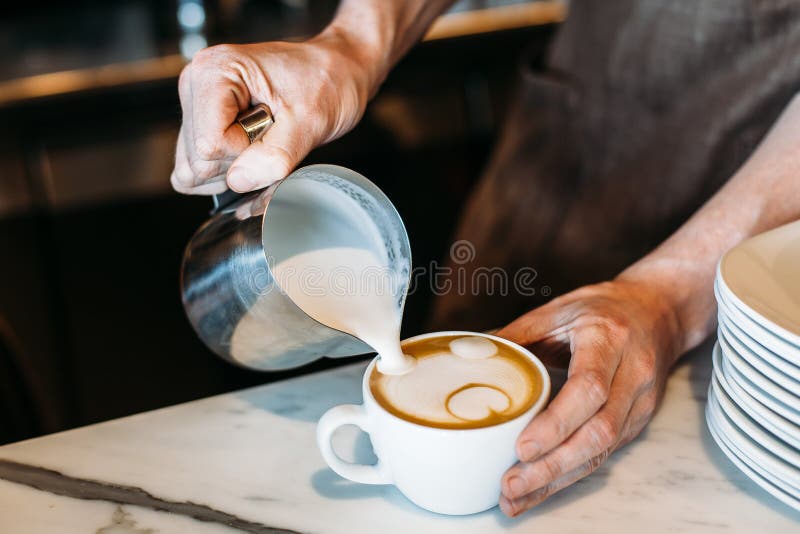 Barista gietend latte schuim over koffie, espresso en het creëren van a