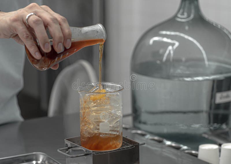 Barista hand holding Lab Borosilicate Glass Beaker Mixing tea drink beverage In Chemistry Bar Beaker Cocktail