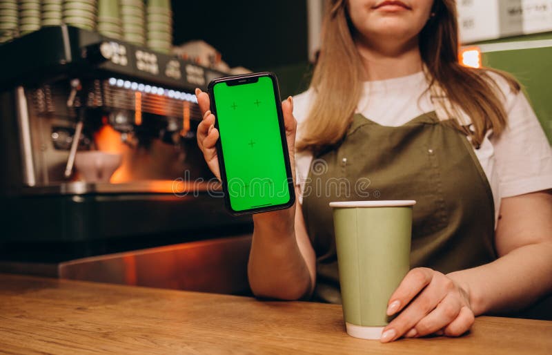 Barista Holds a Green Screen Phone on a Cup of Coffee Stock Image