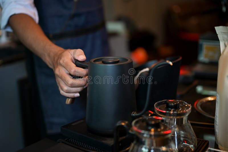 Barista masculină închisă care deține un ceainic turnând apă fierbinte într-o cafea royalty free stock image