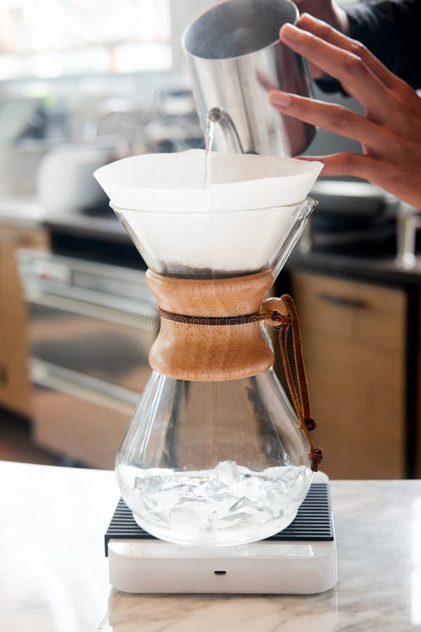 Barista que vierte la agua caliente en la fabricación del café del brebaje del goteo. Barista que vierte la agua caliente sobre el polvo grinded asado del café que hace que el goteo prepara el café