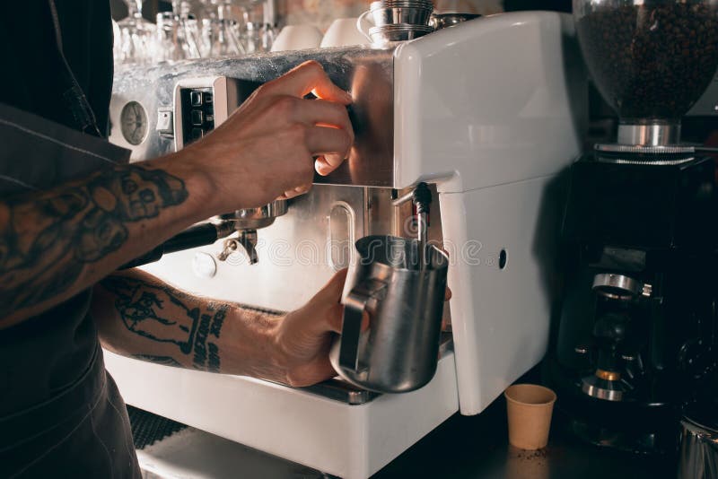 Asian man barista shaking iced black coffee in shaker and pouring in  cocktail glass on bar