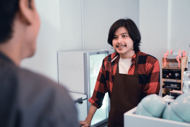 Barista som talar till en kund från stång royaltyfri foto Barista som talar till en kund från stång royaltyfri foto