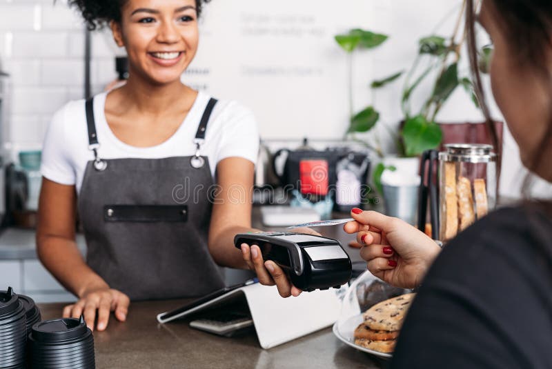 Barista sonriente en apron sosteniendo terminal de pos fotos de archivo libres de regalías
