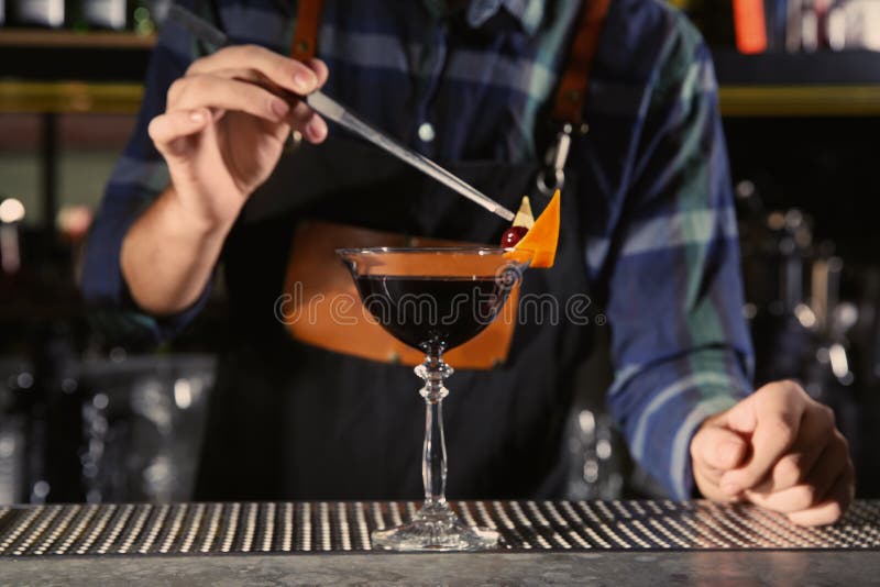 Barman dekoruje alkoholicznego koktajl przy kontuarem w noc klubie zdjęcia stock Barman dekoruje alkoholicznego koktajl przy kontuarem w noc klubie zdjęcia stock