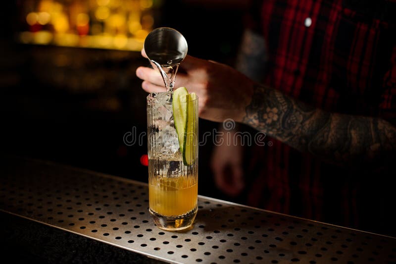 Barman gietende jenever in een glas met komkommer die verse cockt maken royalty-vrije stock foto Barman gietende jenever in een glas met komkommer die verse cockt maken royalty-vrije stock foto
