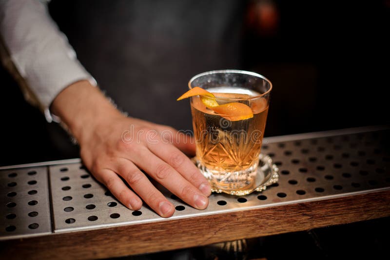 Barman ręka z szkłem świeży staromodny koktajl z pomarańczową łupą zdjęcia royalty free Barman ręka z szkłem świeży staromodny koktajl z pomarańczową łupą zdjęcia royalty free