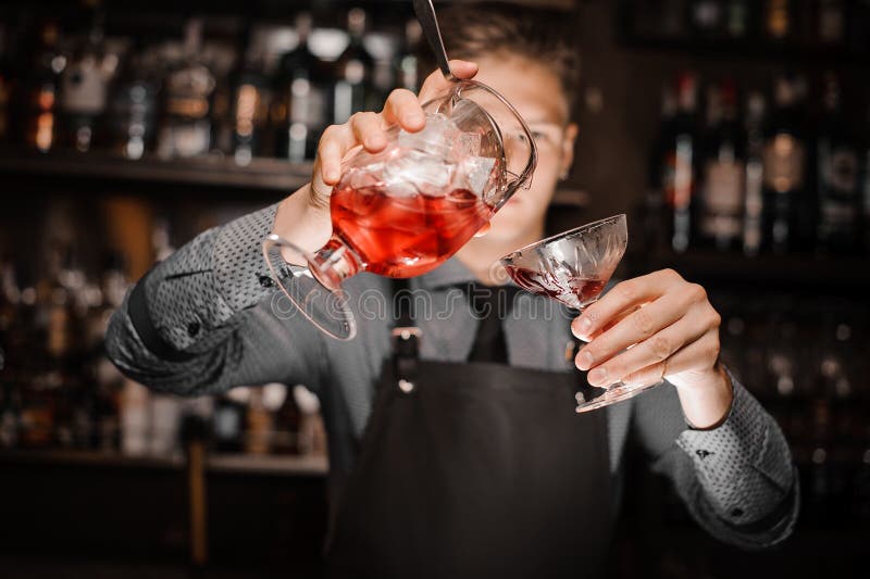 Barman versant un cocktail alcoolique frais dans le verre de cocktail photo libre de droits Barman versant un cocktail alcoolique frais dans le verre de cocktail photo libre de droits